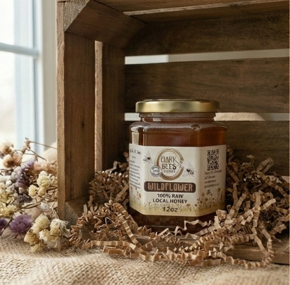 Jar of Clark Bees wildflower honey inside a crate surrounded by dried flowers.